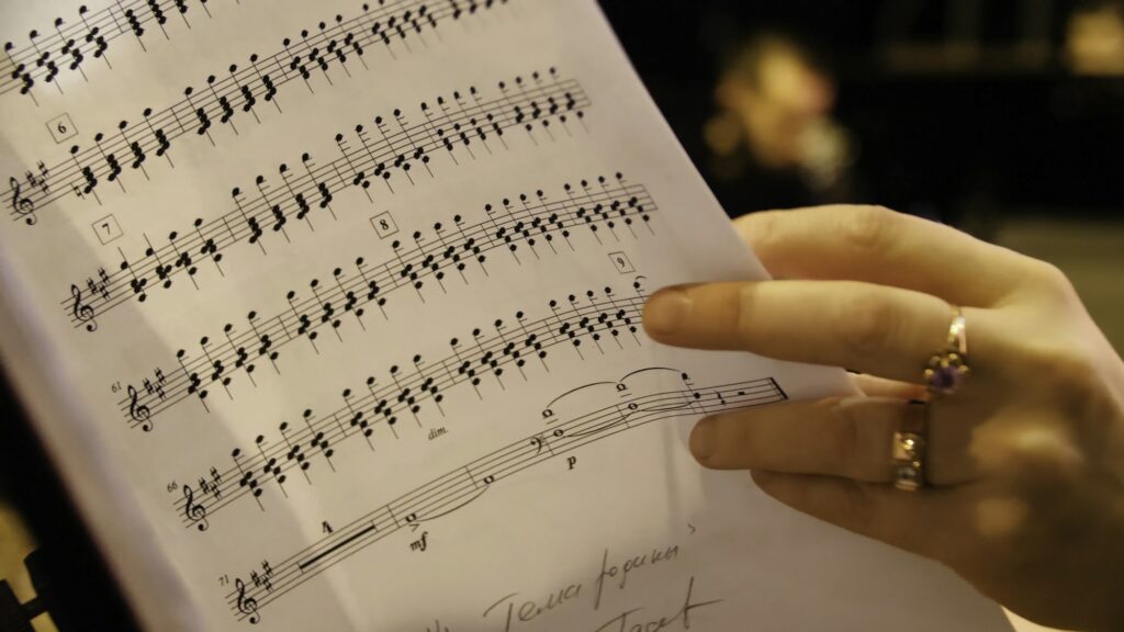 Beautiful female music composer looking at music notes. Woman looks at notes on piano closeup